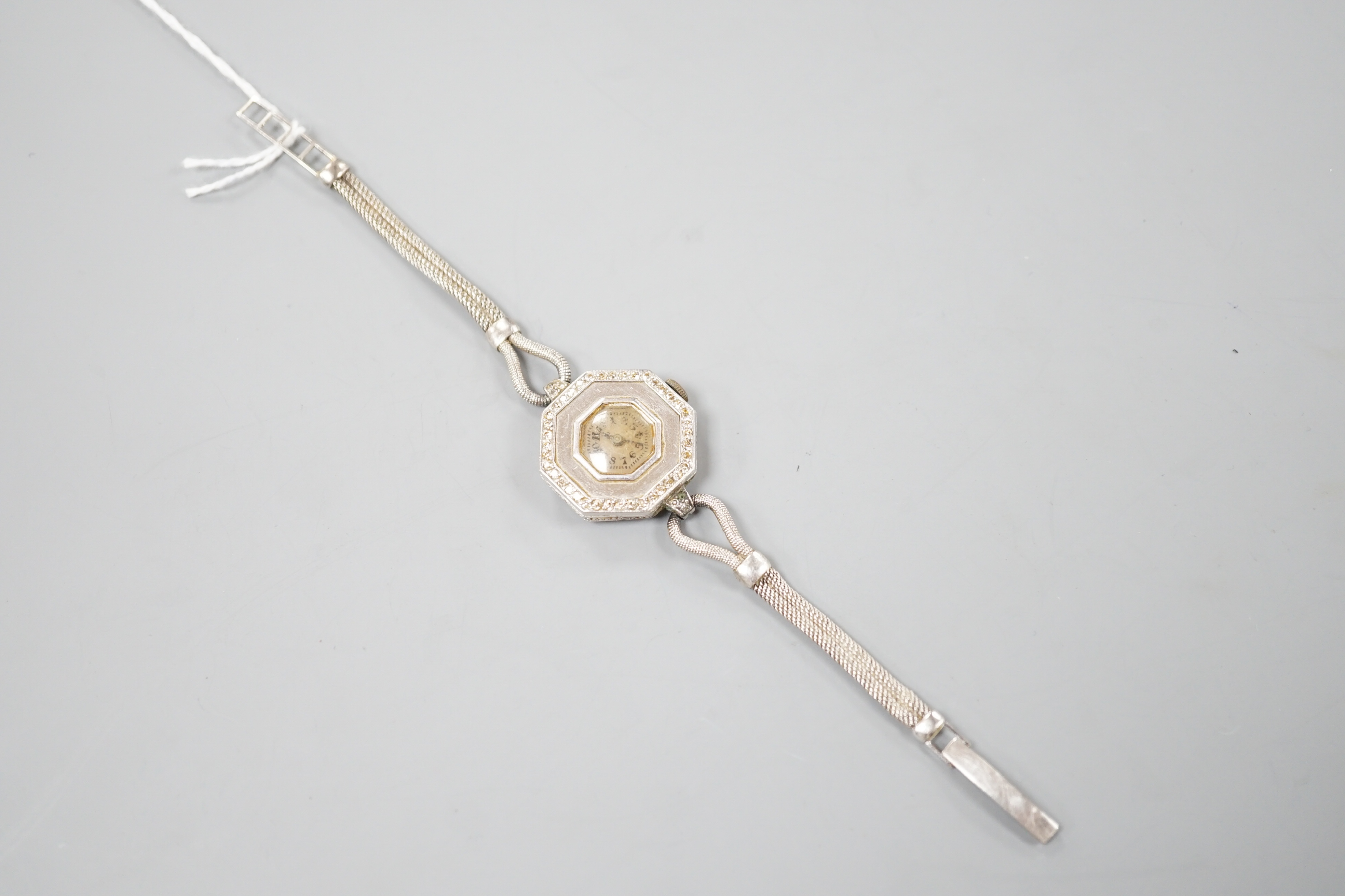A lady's early 20th century white metal and diamond chip set manual wind octagonal cocktail watch, on a white metal twin strand mesh bracelet, gross 27.4 grams.